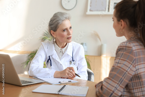 Middle aged female doctor therapist in consultation with patient in office.