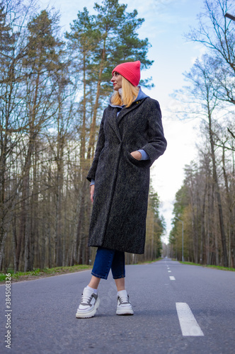 The girl stands on the road in the forest.