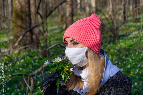 Girl in a mask in the forest with a bouquet of flowers. photo