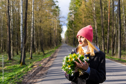 A girl with a bouquet of flowers stands on the road.