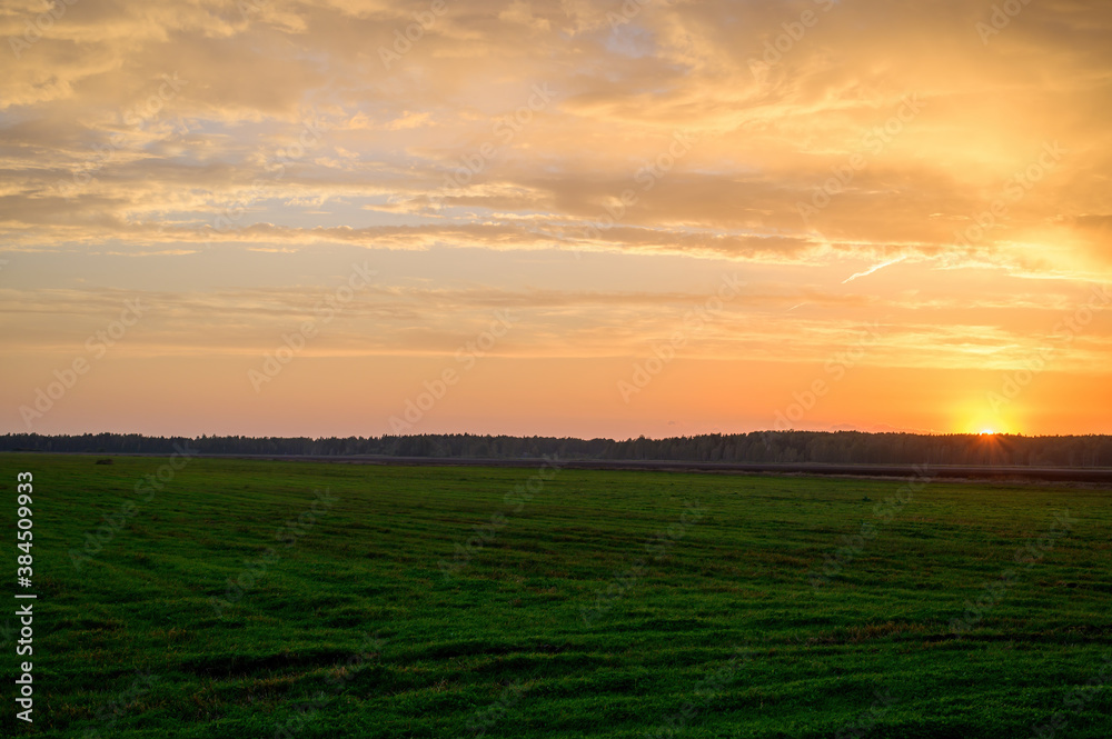 Photo of the evening sunset sky in autumn against the background of a green field