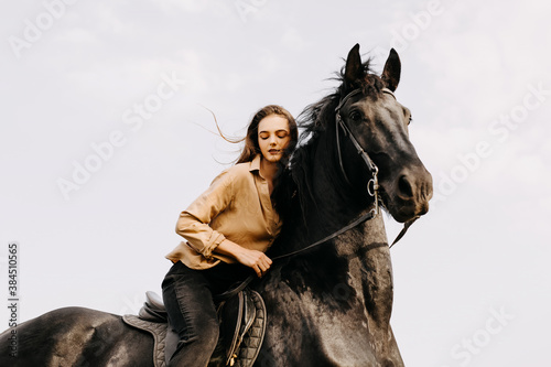Young woman riding a black horse, outdoors.