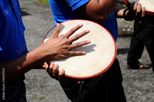 KUALA LUMPUR, MALAYSIA -MARCH 2, 2019: Boy plays kompang during Malay traditional wedding ceremony. They will sing songs together while playing the kompang.Kompang is a Malay traditional drums.  photo
