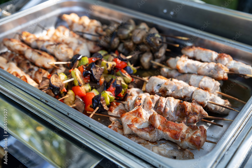Сatering banquet. Meat and vegetable barbeque on skewers in a chafing dish