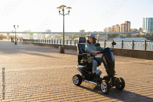 Woman tourist riding a four wheel mobility electric scooter on a city street.	