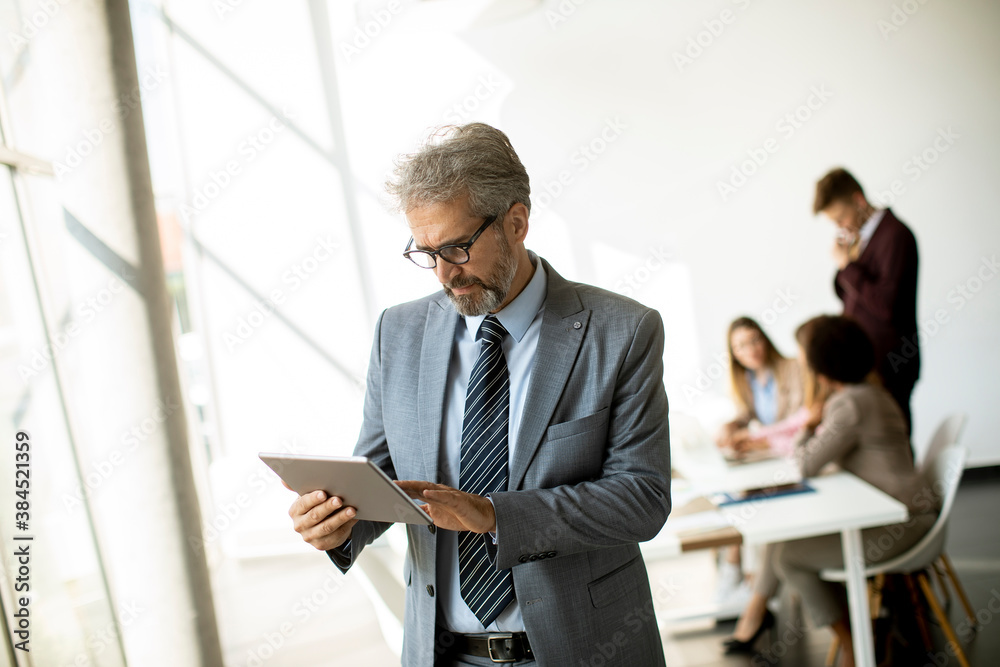 Handsome mature businessman using his tablet in the office Handsome mature businessman using his tablet in the office
