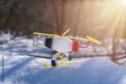 DIY toy helicopter made of waste and plastic bottles on snow background. Recycle crafts. photo