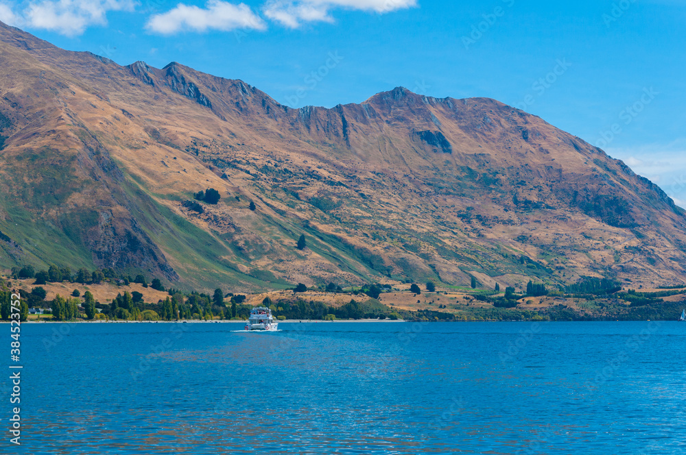 Tourist cruise boat sailing on Wanaka lake with amazing view over mountains, South Island, New Zealand Tourist cruise boat sailing on Wanaka lake with amazing view over mountains, South Island, New Zealand