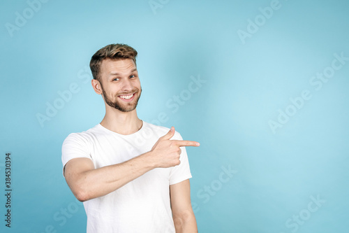 Happy young man pointing aside with finger