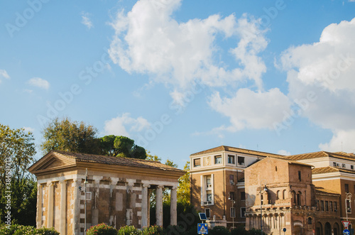 Rome, Italy - The ancient roman Temple of Portunus blended in the modern italian city of Rome during the afternoon with clouds in the blue sky.