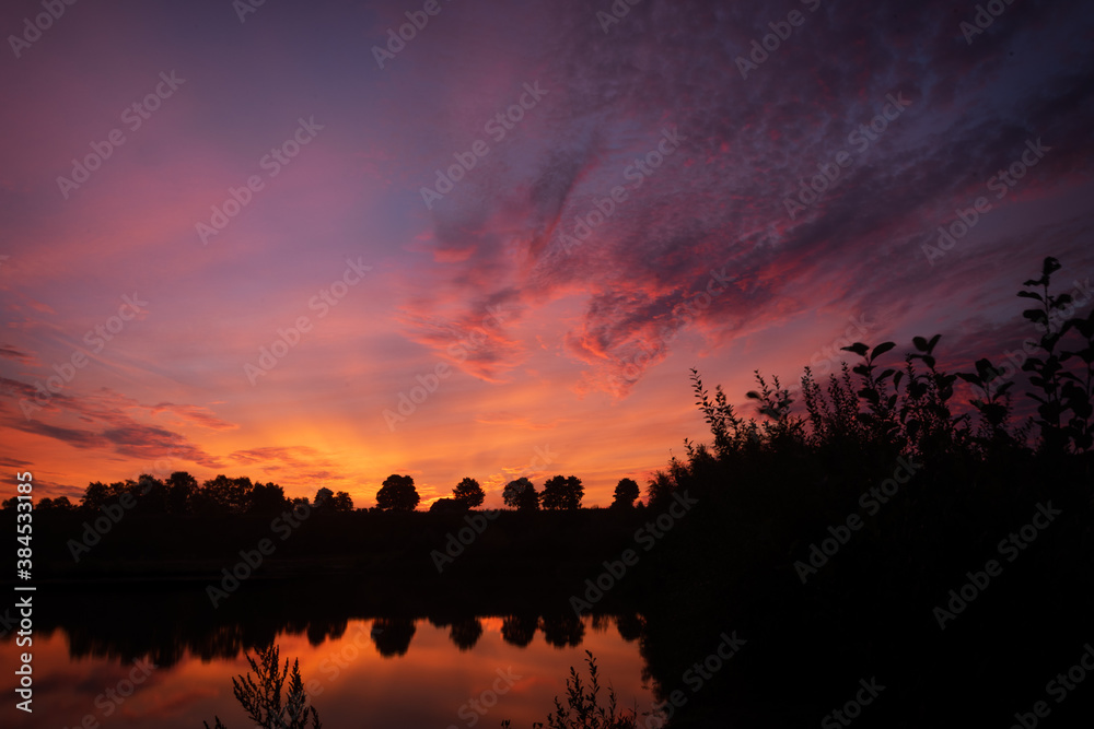 Obraz premium A breathtaking colorful dawn which gets reflected in the water, with a beatiful sky.