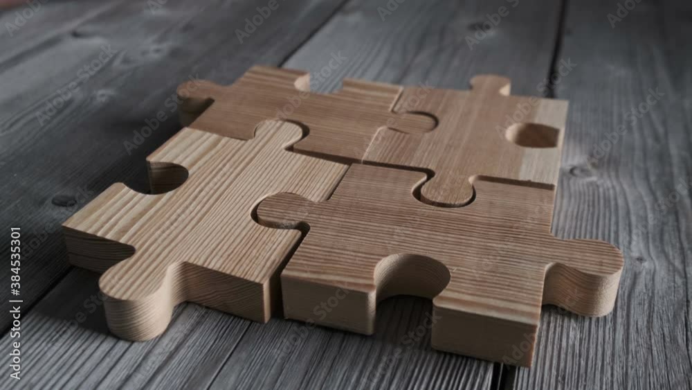 Business people assembling wooden puzzle on work table, teamwork concept