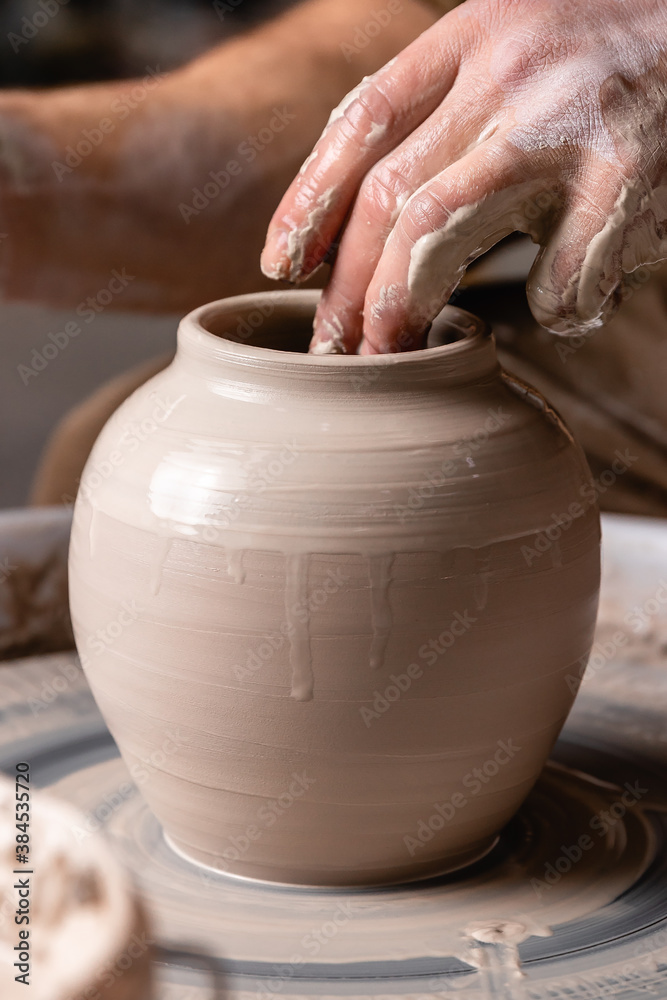 Potter making a jar or pot of white clay on the wheel circle in studio. concept of creativity, art and manual work Potter making a jar or pot of white clay on the wheel circle in studio. concept of creativity, art and manual work