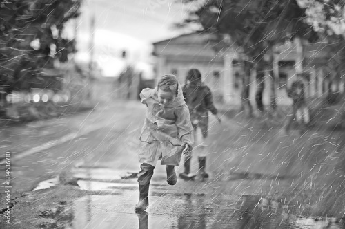 child in a raincoat plays outside in the rain / seasonal photo, autumn weather, warm clothes for children