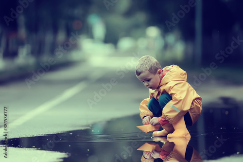 a boy plays boats in a puddle / childhood, walk, autumn game in the park, a child on a walk
