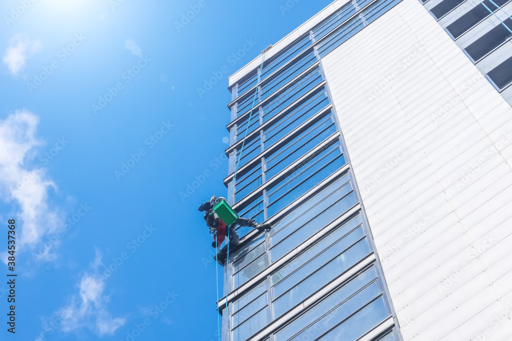 Climber clean windows from the outside of the building washing the glazing of the facade of a multi-storey building. Climber clean windows from the outside of the building washing the glazing of the facade of a multi-storey building.
