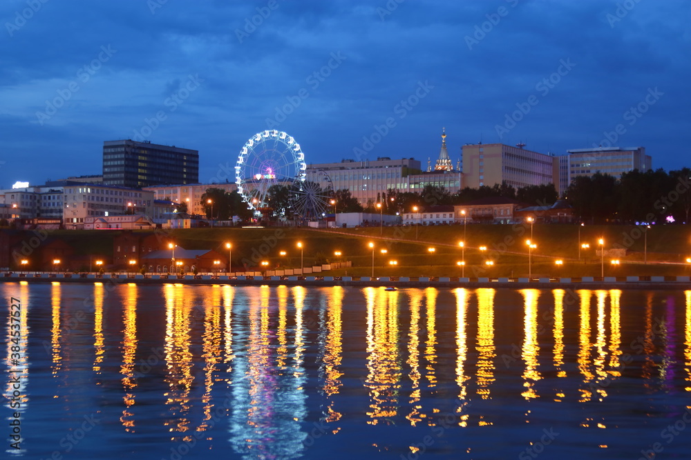 view from the pond to the city at night with a ferris wheel