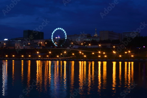 view from the pond to the city at night with a ferris wheel