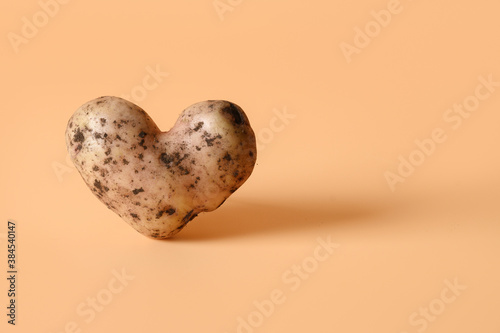 Abnormal potato in shape of heart on beige background. Concept love organic natural homegrown ugly vegetables. Close up. Copy space.