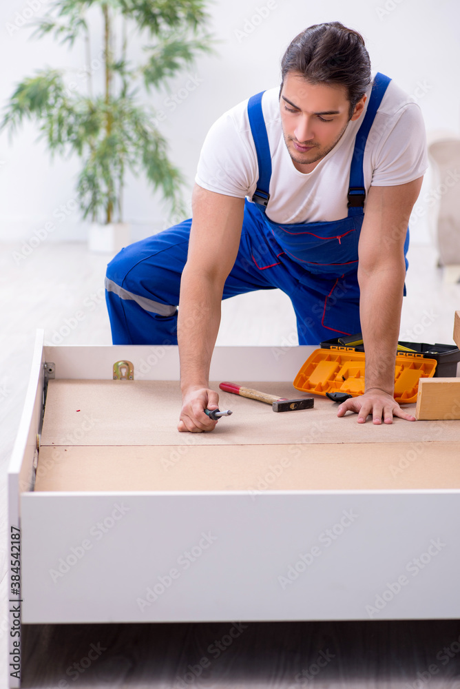 Young male contractor installing furniture at home Young male contractor installing furniture at home