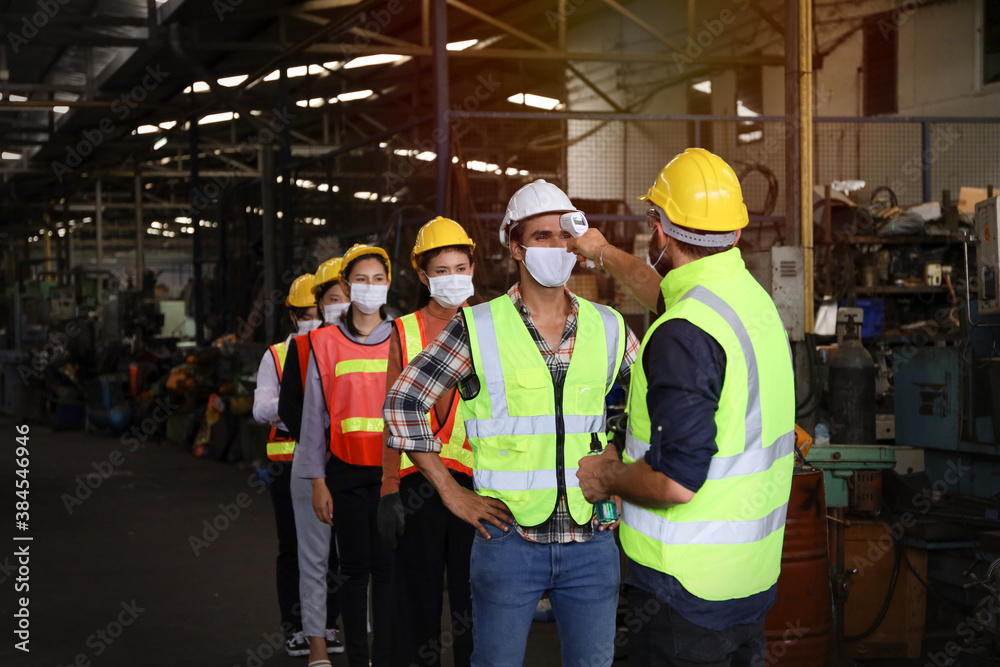 Supervisor use meter to measure temperature degree   of employees or engineer before work in factory, Covid-19 screen and protection, team wear face mask while working in manufacturing 