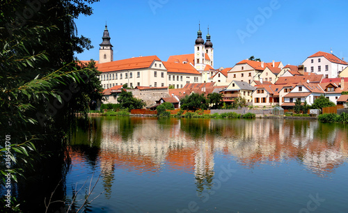 View of Telc town across the lake with reflections of the buildings in the water