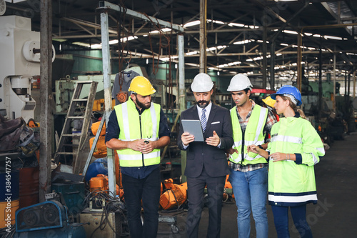 Leader or manager using tablet and meeting with engineer and technician while line walk in factory workplace, team wear face mask whine working at maintenance machine shop 
