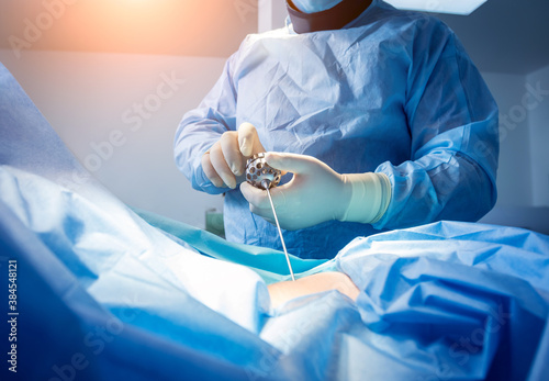 Surgeon performs endoscopic microdiscectomy of herniated intervertebral disc.