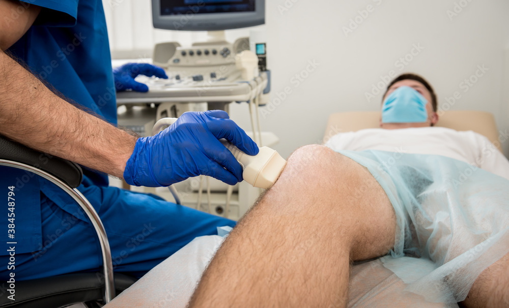 Doctor doing an ultrasound of the mans knee. Doctor doing an ultrasound of the mans knee.