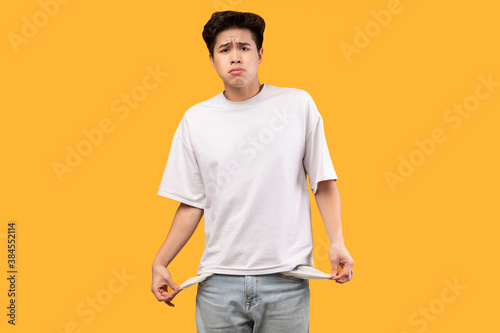 Portrait of asian guy showing his empty pockets © Prostock-studio