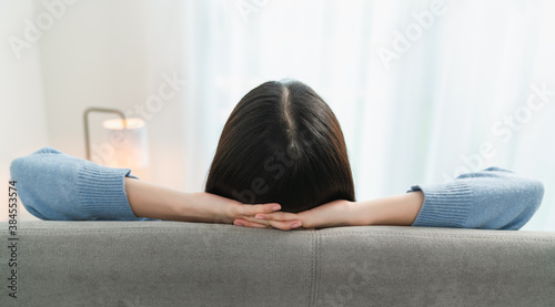 Back view of woman resting comfortably and relaxing on a sofa after work at home.