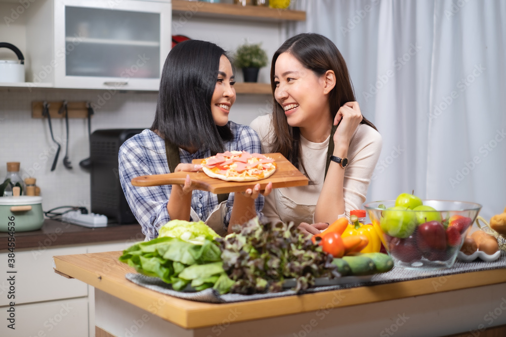 LGBT Lesbian couple love moments cooking Healthy vegetable salad at home.Two young beautiful women girlfriends lesbian couple cook at home in the kitchen cuddling and laughing