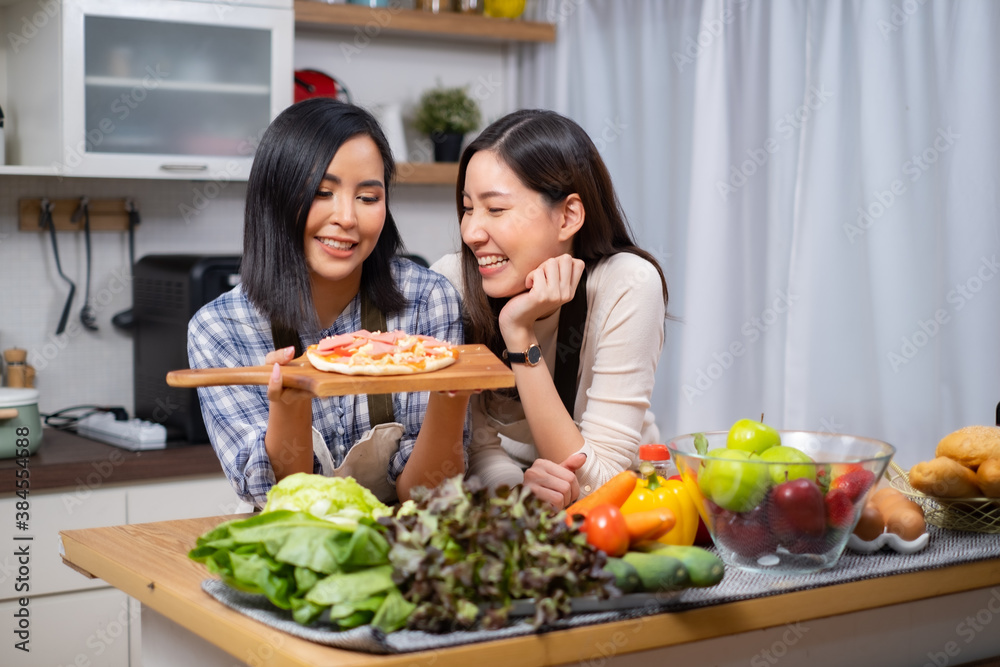 LGBT Lesbian couple love moments cooking Healthy vegetable salad at home.Two young beautiful women girlfriends lesbian couple cook at home in the kitchen cuddling and laughing