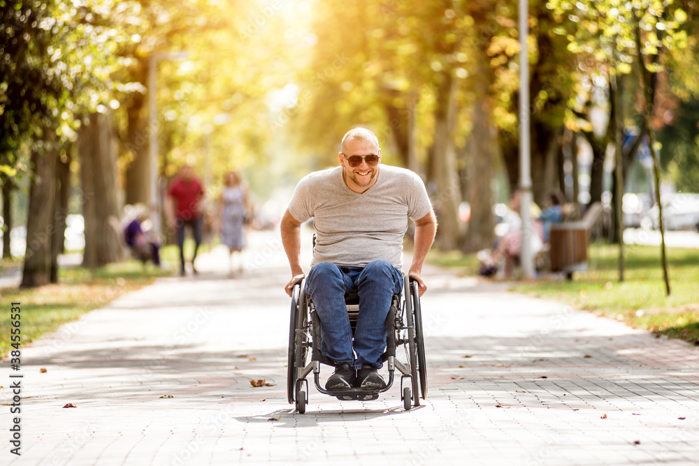 Handicapped man in wheelchair walk at the park alley