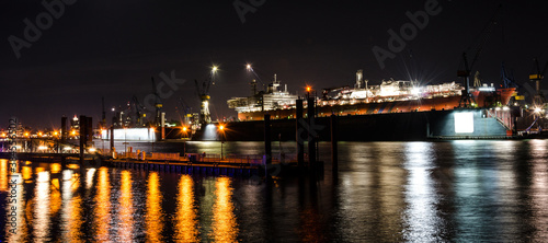 Scenic widescreen night shot of large container vessel under repair in the dock on the Elbe river in Hamburg, Germany
