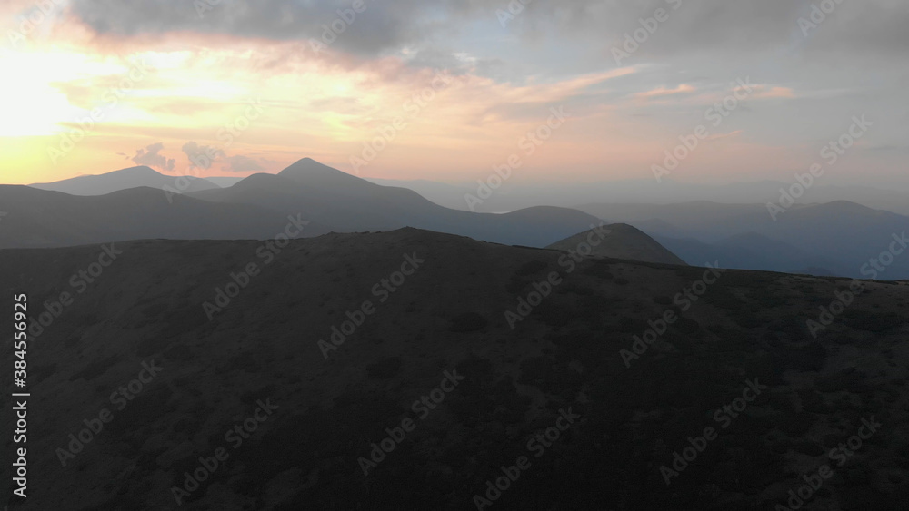 Dark mountain against the background of the rising sun. Gloomy foggy mountains and a cloudy sky illuminated by the first rays of the sun. Dark mountain against the background of the rising sun. Gloomy foggy mountains and a cloudy sky illuminated by the first rays of the sun.