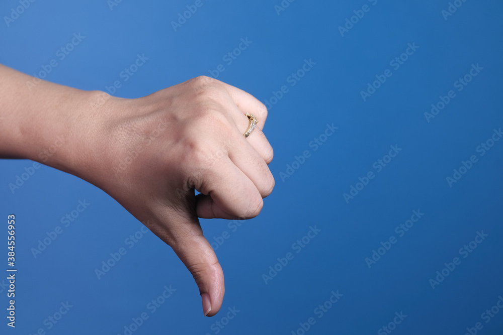 hand showing thumb down sign on blue background. hand showing thumb down sign on blue background.