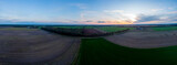 Sunset aerial 180 degrees panorama of Dutch agrarian farmland landscape against blue sky with colourful orange tint.
