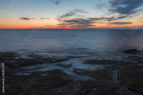 Twilight sunset over rocky shore of Baltic sea. Almost clear sky and orange strap along the horison. Estonia. © yegorov_nick