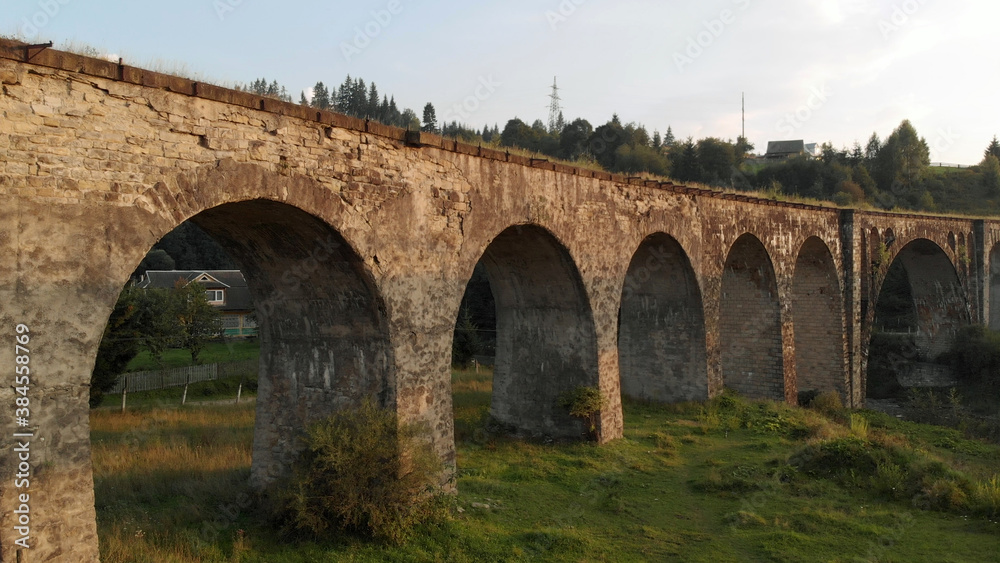 Ancient bridge in mountain village. Summer landscape of abandoned railway bridge.