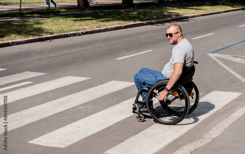 Handicapped man in wheelchair crossing street road