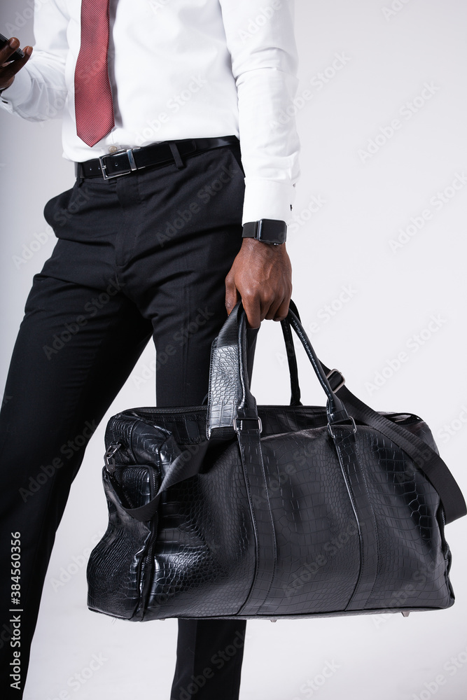 An African American man goes on a business trip with a large travel bag. Close-up of a suitcase in hand An African American man goes on a business trip with a large travel bag. Close-up of a suitcase in hand