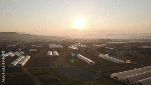 Aerial view of wide field with greenhouses. Beautiful landscape of sunset.