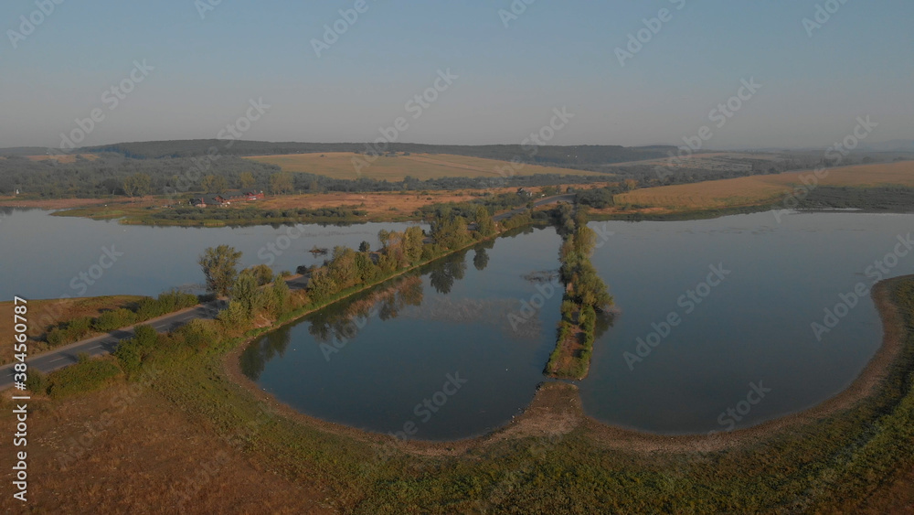 Landscape of amazing lake in mountains. An asphalt road divides the lake into two parts. A house on the lake in the distance.