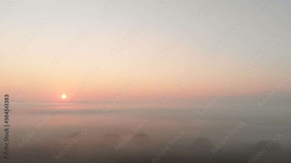 Beautiful sunrise landscape. The sun shining through the white thick fog. Purple dull sunshine in the morning sky. Beautiful sunrise landscape. The sun shining through the white thick fog. Purple dull sunshine in the morning sky.