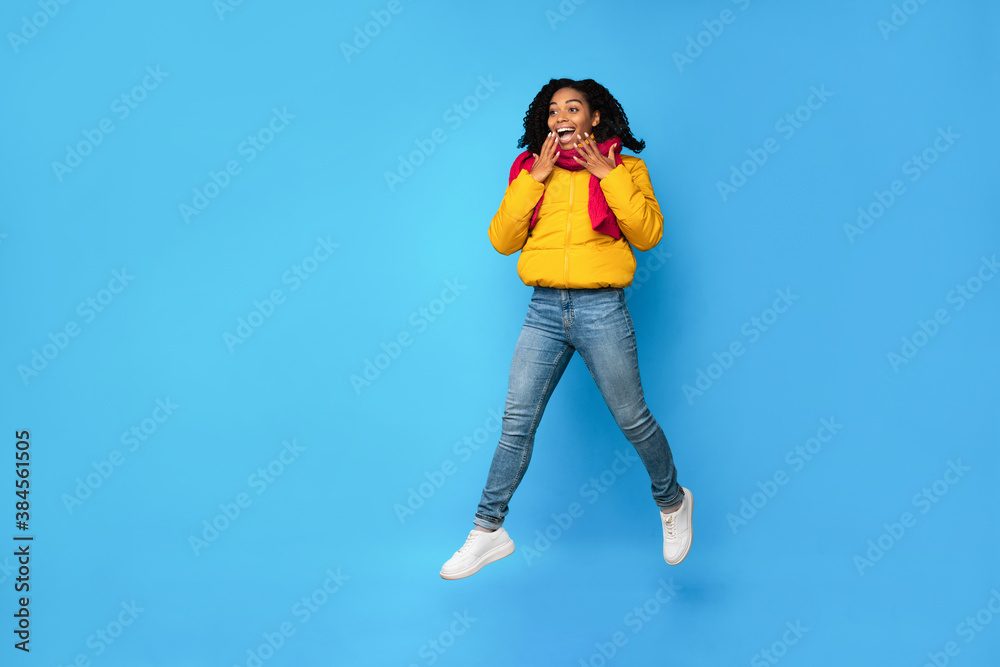 Excited Black Woman Jumping Looking Aside Over Blue Background