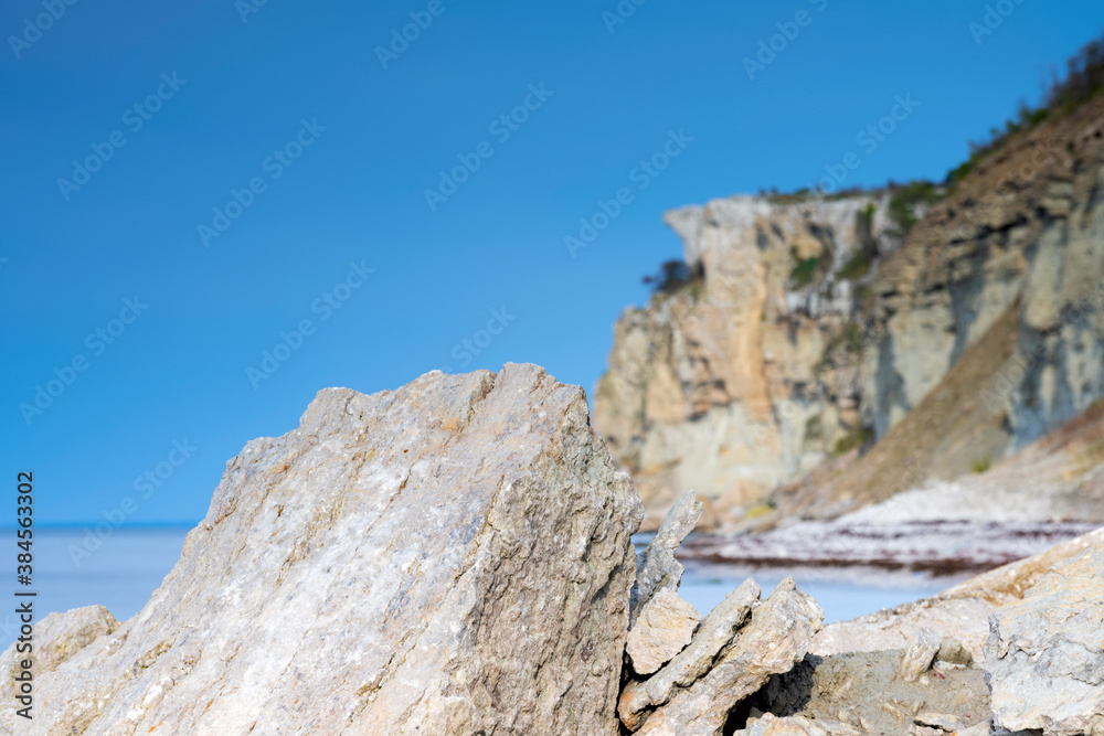 Limestone cliff next to ocean with boulders in foreground Limestone cliff next to ocean with boulders in foreground