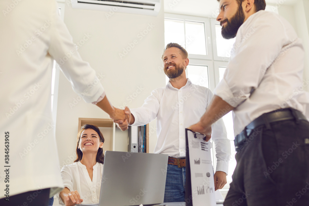 Handshake of positive business people in office after successful negotiations