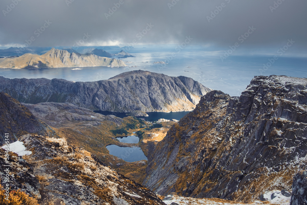 Beautiful Mountains above fishing town of Nusfjord, Norway, Lofoten islands, golden autumn surrounded by colorful mountains and blue water