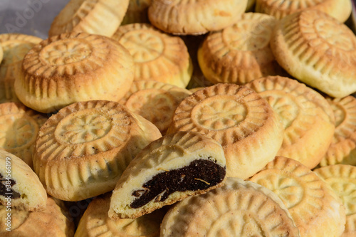 Close up of traditional oriental sweet filled pastry cookies known as mamul or Mamoul, Arab desert with sugar,  walnuts and dates, in display at an weekend street food market, top view, soft focus.